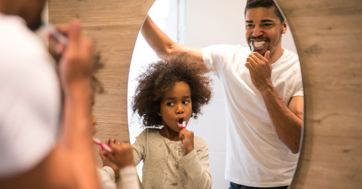 a father and daughter brush teeth together 