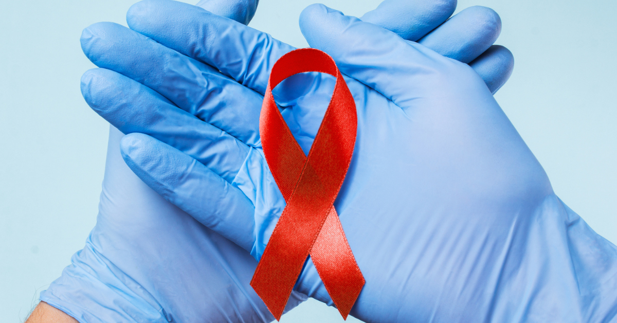 Two hands with blue latex medical gloves on pushed together with palms facing up, holding a red oral cancer ribbon.