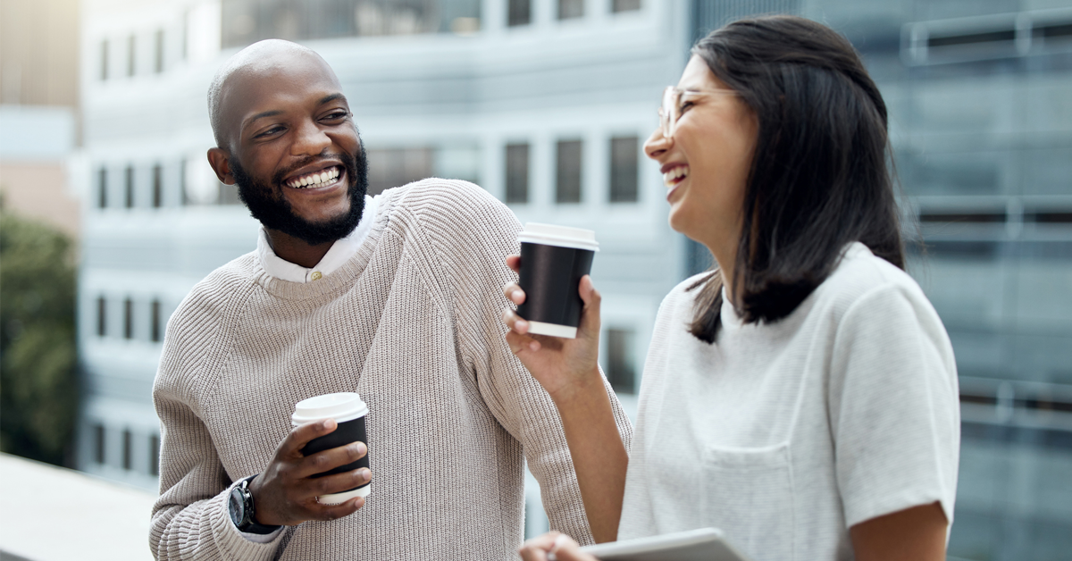 a man and woman co-worker chat over a coffee break at work