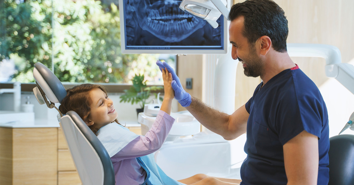 a young girl high-fives a dental teammate to celebrate good oral health