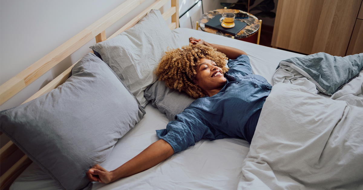 A Black woman wakes up with a smile on her face after a great night's rest. She is now ready to take on another day at the office.