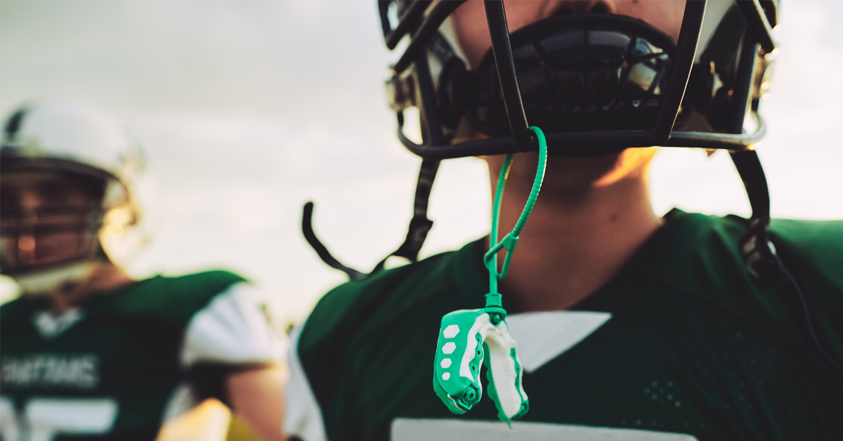 a young American football player with a mouthguard in the foreground 