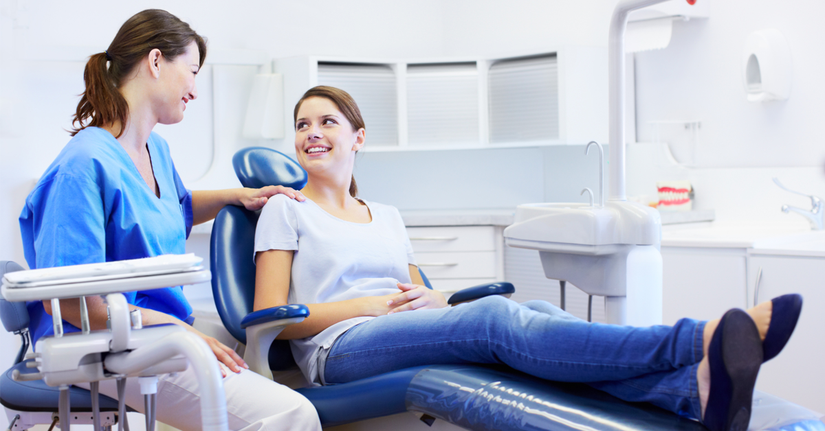 a dentist gives a happy patient a comforting smile