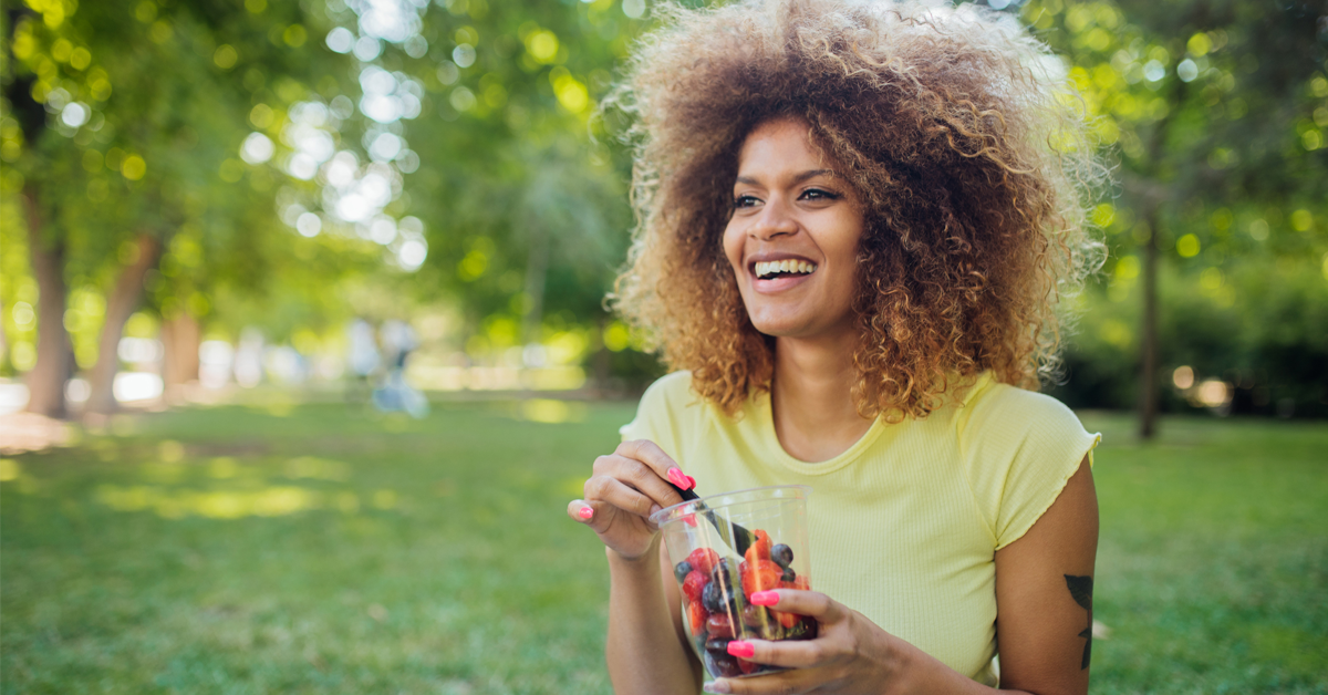 a Black woman enjoys a snack of mixed berries, which are full of vitamins and nutrients